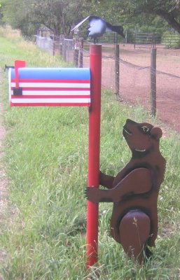 Bear holding rural mailbox.
