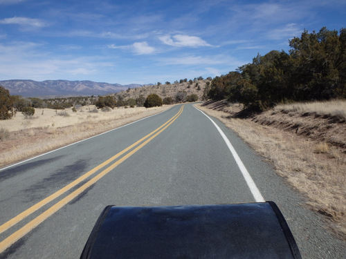 The handlebar-bag, sans map, is heading southwest on NM-220.